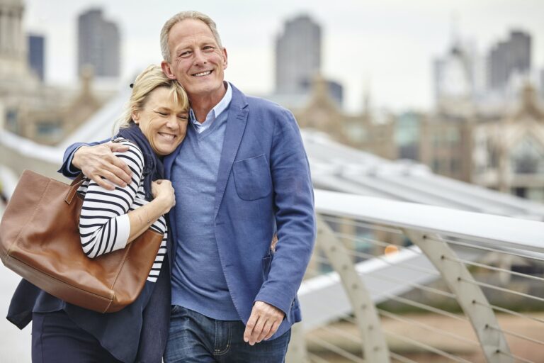 Mature dating couple strolling across Millennium Bridge, London, UK